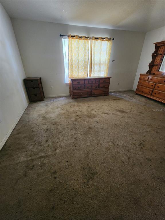 A bedroom with stained wall-to-wall carpeting, a window with yellow curtains, and wooden furniture — 2102 ROTTWELL COURT, BRANDON, FL