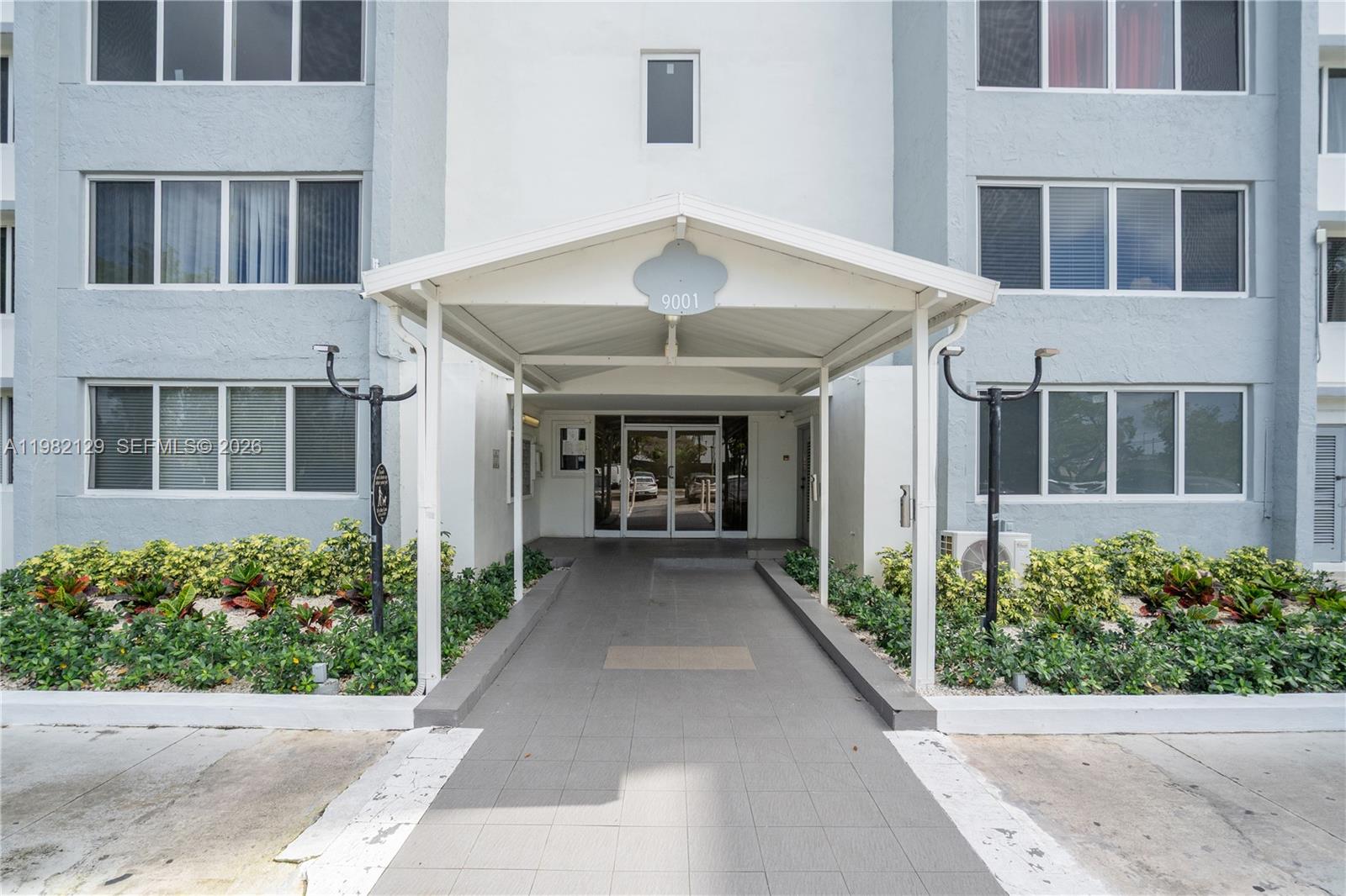The exterior entrance of a multi-story apartment building features a covered walkway and landscaping — 9001 SW 77th Ave # C402, Miami FL 33156, MIAMI, FL