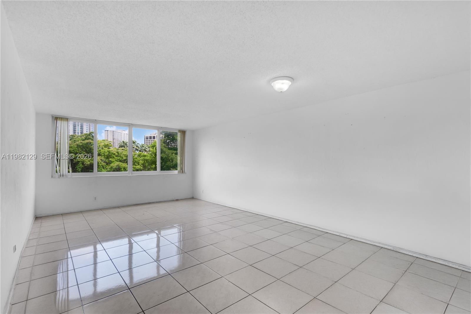 An empty room with white walls, light-colored tile flooring, and a large window — 9001 SW 77th Ave # C402, Miami FL 33156, MIAMI, FL