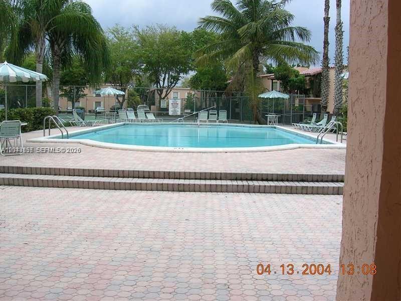 An outdoor swimming pool with a brick patio and lounge chairs surrounded by palm trees — 10794 N Kendall Dr # B22, Miami FL 33176, MIAMI, FL