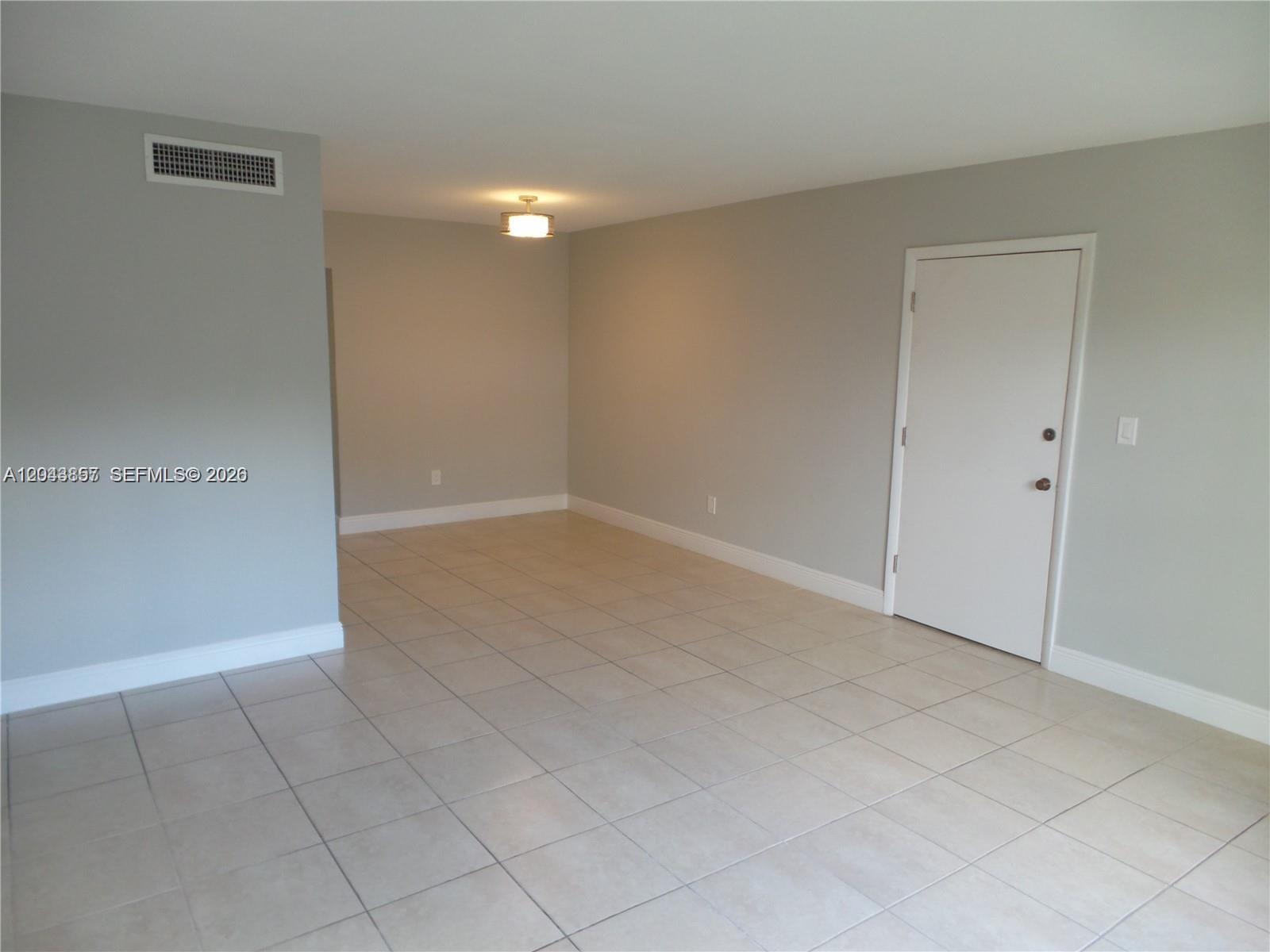 An empty room features light gray walls, beige tile flooring, and a white door — 10794 N Kendall Dr # B22, Miami FL 33176, MIAMI, FL