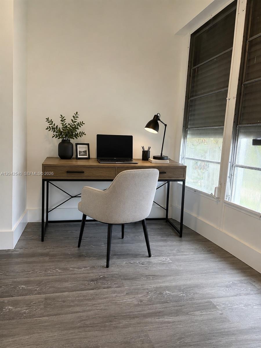 A home office features a wooden desk, a gray upholstered chair, and a black lamp — 1951 NE 39th St # 138, Lighthouse Point FL 33064, LIGHTHOUSE POINT, FL
