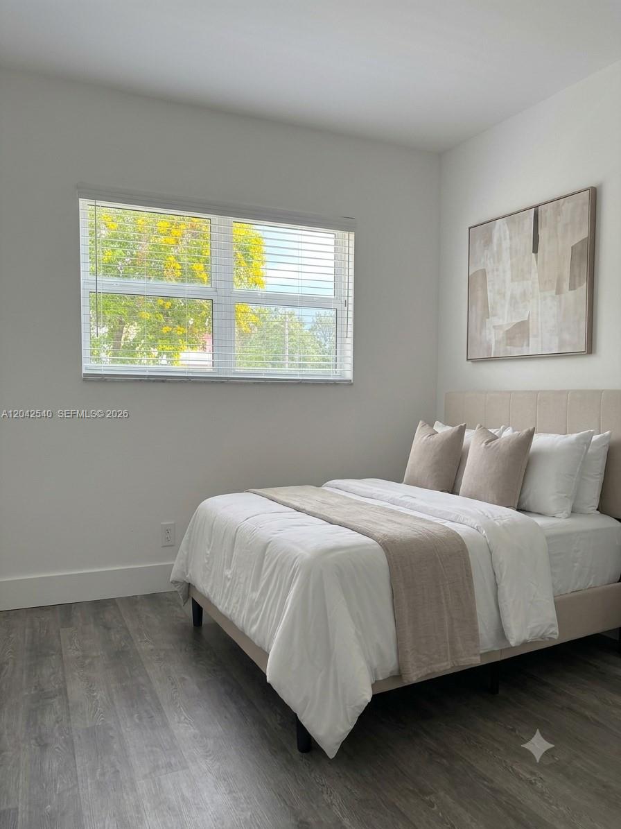 A bedroom features a bed with neutral bedding, a window with blinds, and wall art — 1951 NE 39th St # 138, Lighthouse Point FL 33064, LIGHTHOUSE POINT, FL