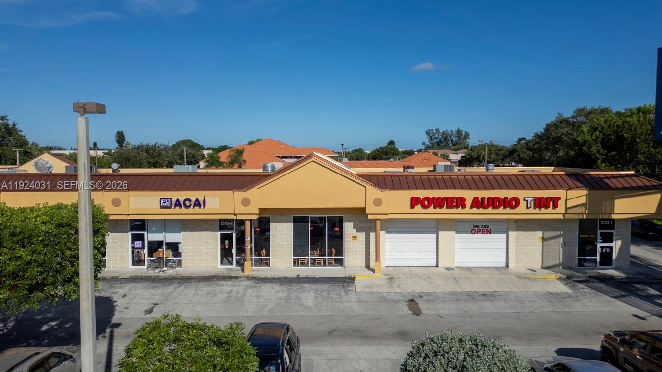 An exterior view of a single-story commercial strip mall with two storefronts under a brown roof — 23133 Sandalfoot Plaza Dr, Boca Raton FL 33428, BOCA RATON, FL