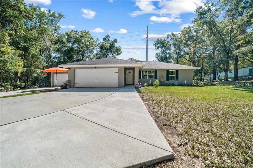 A single-story house with a two-car garage, concrete driveway, and surrounding trees — 543 N ROOKS AVENUE, INVERNESS, FL
