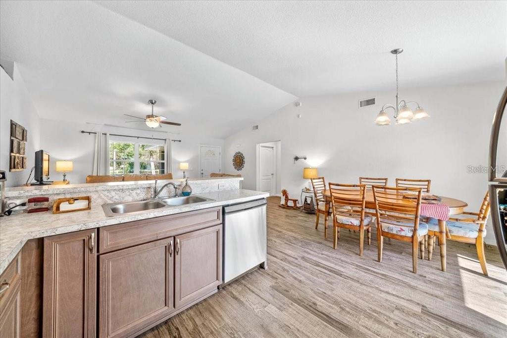 A kitchen with granite countertops and wood cabinets overlooks a dining area and living room — 543 N ROOKS AVENUE, INVERNESS, FL