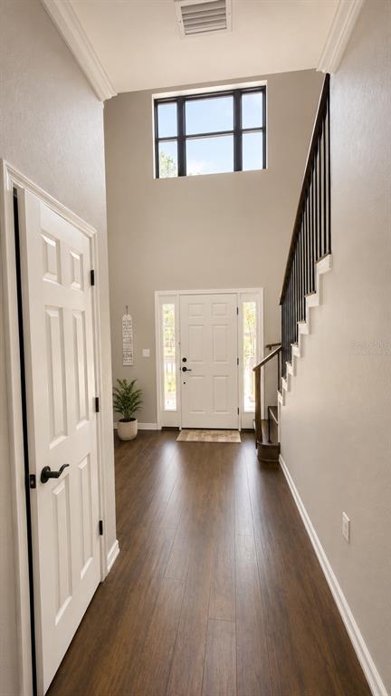 A bright entryway features wood-look flooring, a white front door, and a staircase with railings — 14831 SE 1ST PLACE, WILLISTON, FL