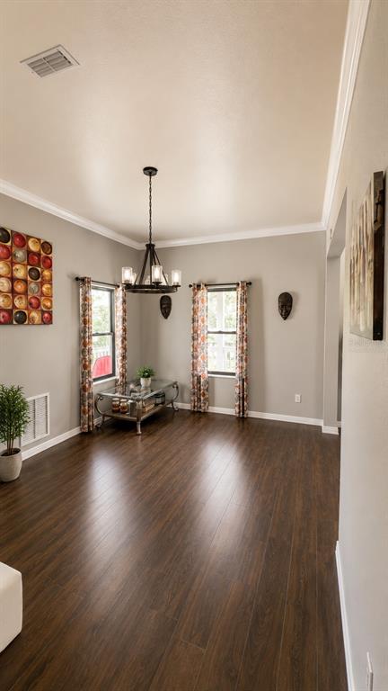 A dining room features dark wood flooring, a chandelier, and two windows with patterned curtains — 14831 SE 1ST PLACE, WILLISTON, FL