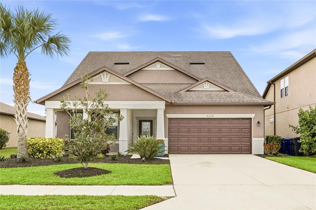 A single-story suburban house features a brown garage, a covered entryway, and a palm tree — 6224 KEVESTA AVENUE, PALMETTO, FL