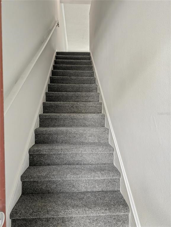 A straight staircase with gray carpet leads upward between two plain white walls — 5701 BENTGRASS DRIVE UNIT 18-207, SARASOTA, FL