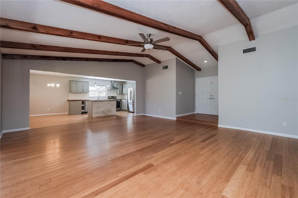 A spacious living room with vaulted ceilings, exposed wood beams, and light hardwood flooring — 515 SANDALWOOD DRIVE, PLANT CITY, FL
