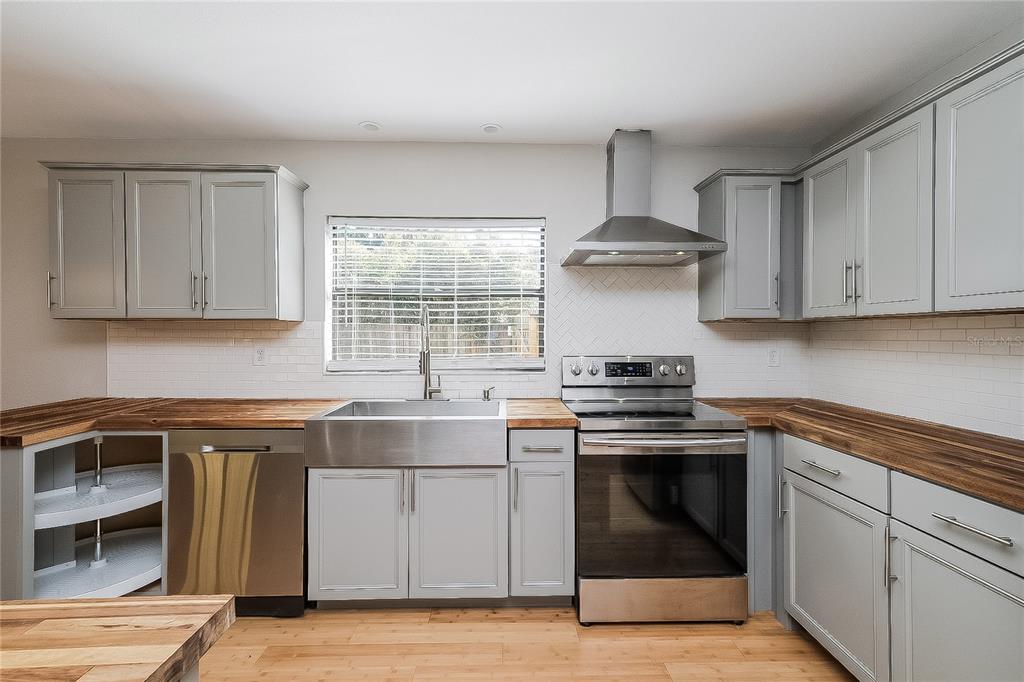 A kitchen features gray cabinets, wood countertops, stainless steel appliances, and a farmhouse sink — 515 SANDALWOOD DRIVE, PLANT CITY, FL