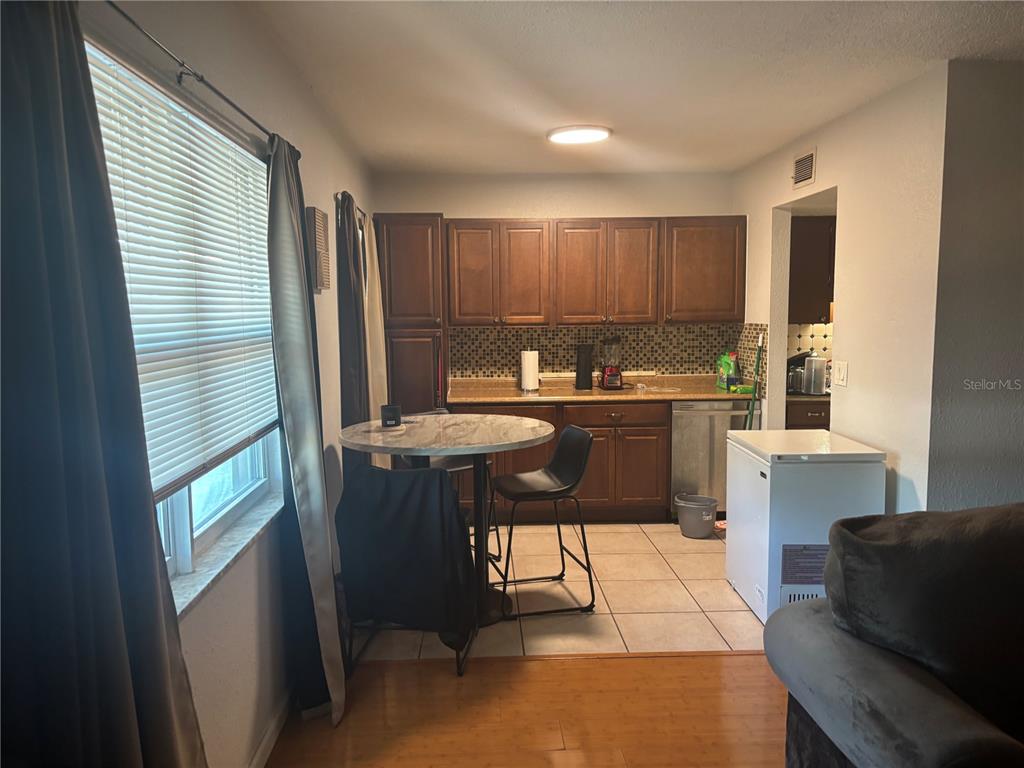 A kitchen features wood cabinets, a tiled backsplash, a small dining table, and tile flooring — 6080 22ND AVENUE N UNIT 3, ST PETERSBURG, FL