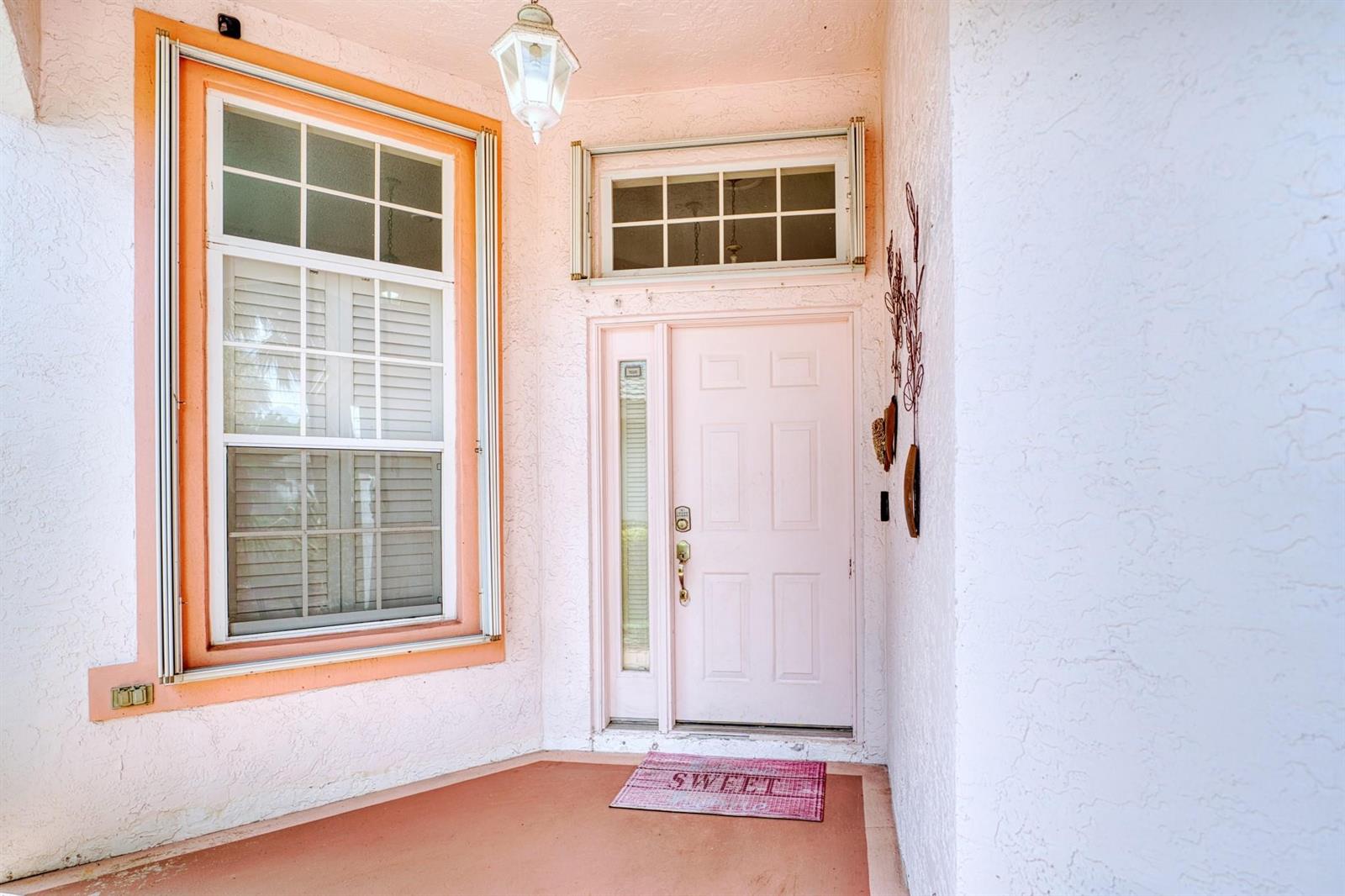 A pink front door and a large window are on the porch of a house — 2824 Waters Edge Circle, FL 33413, FL