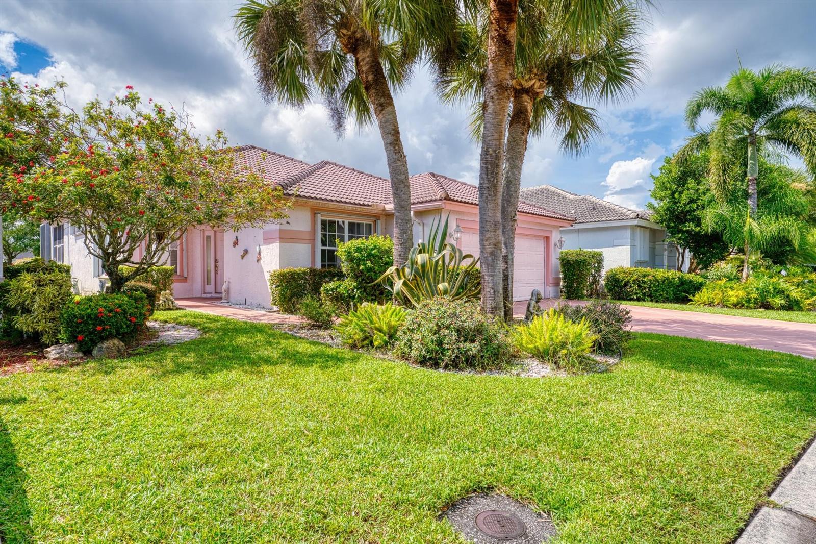 A single-story pink house with a tile roof, palm trees, and a landscaped front yard — 2824 Waters Edge Circle, FL 33413, FL