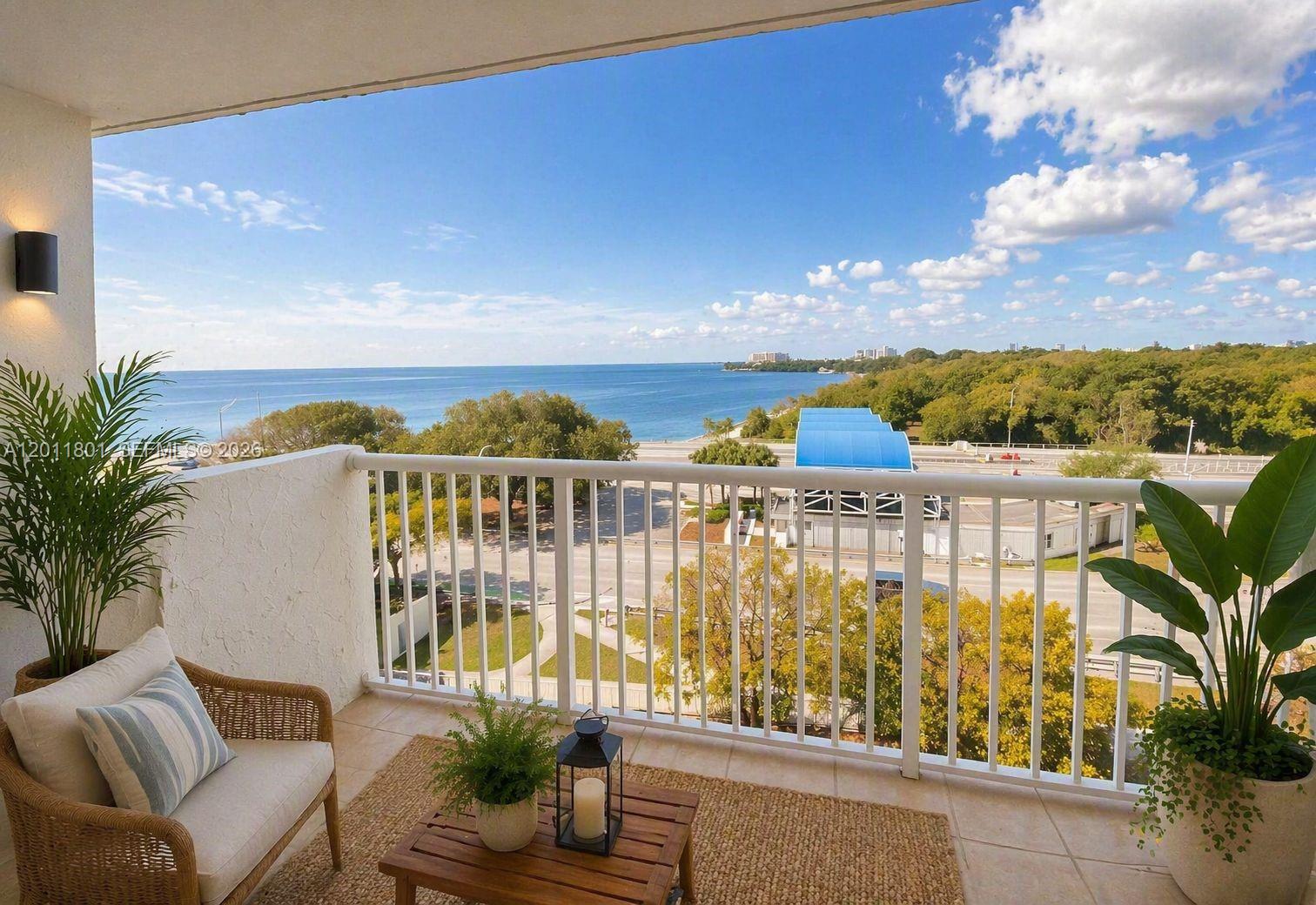 A balcony with a wicker chair, a small table, and a view of the ocean — 150 SE 25th Rd # 8i, Miami FL 33129, MIAMI, FL