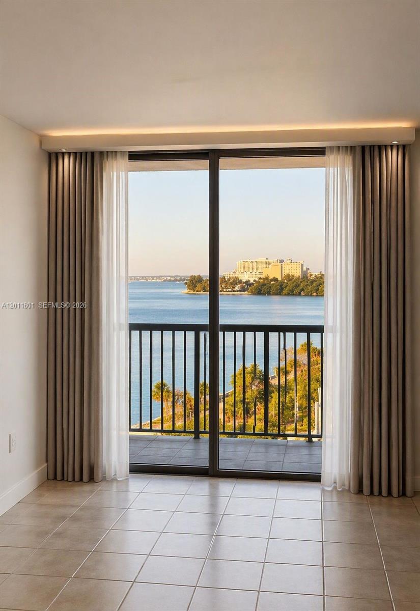 A room with tiled floors features floor-to-ceiling curtains and a sliding door overlooking water — 150 SE 25th Rd # 8i, Miami FL 33129, MIAMI, FL