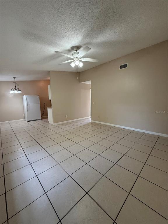 A room with light-colored tile flooring, a ceiling fan, and a white refrigerator — 1619 S HIGH STREET, DELAND, FL