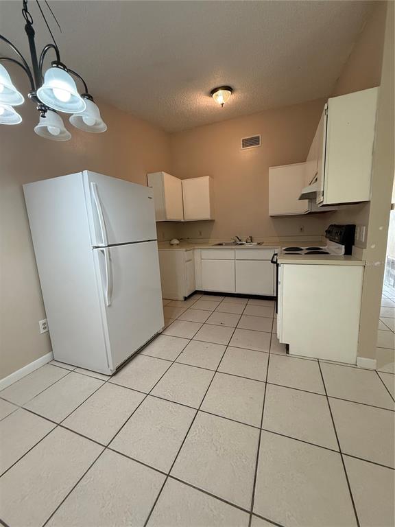 A kitchen features white appliances, white cabinets, and light-colored floor tiles — 1619 S HIGH STREET, DELAND, FL