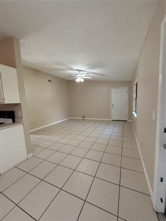 An open living area features beige walls, a ceiling fan, and light-colored floor tiles — 1619 S HIGH STREET, DELAND, FL