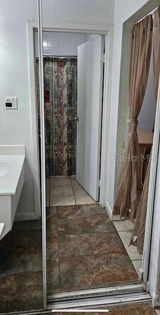 A bathroom view reflected in a mirrored closet door with tiled floors and a shower curtain — 43420 HIGHWAY 27 UNIT 242, DAVENPORT, FL