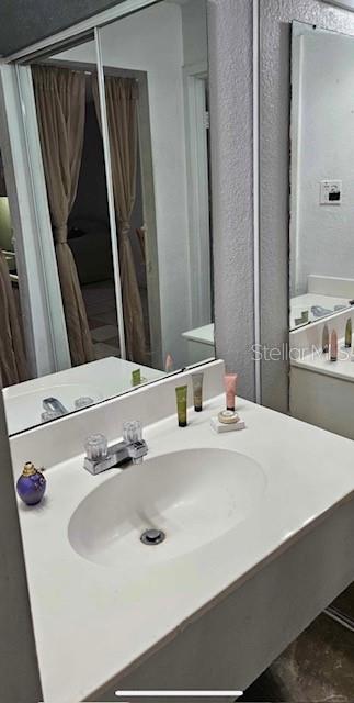 A bathroom vanity with a white countertop, oval sink, and a large mirror — 43420 HIGHWAY 27 UNIT 242, DAVENPORT, FL