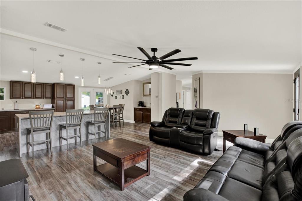 An open-concept living room and kitchen featuring dark wood cabinetry, a kitchen island, and leather furniture — 13611 MCINTOSH DRIVE, DADE CITY, FL