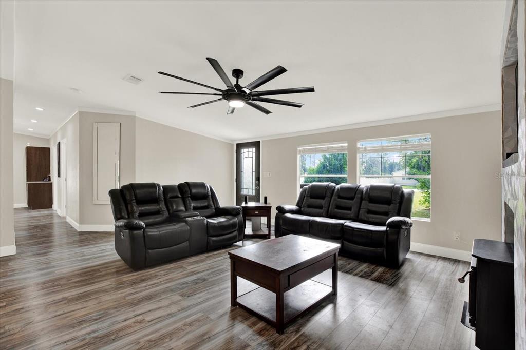 A living room features dark leather sofas, a wooden coffee table, and wood-look flooring — 13611 MCINTOSH DRIVE, DADE CITY, FL