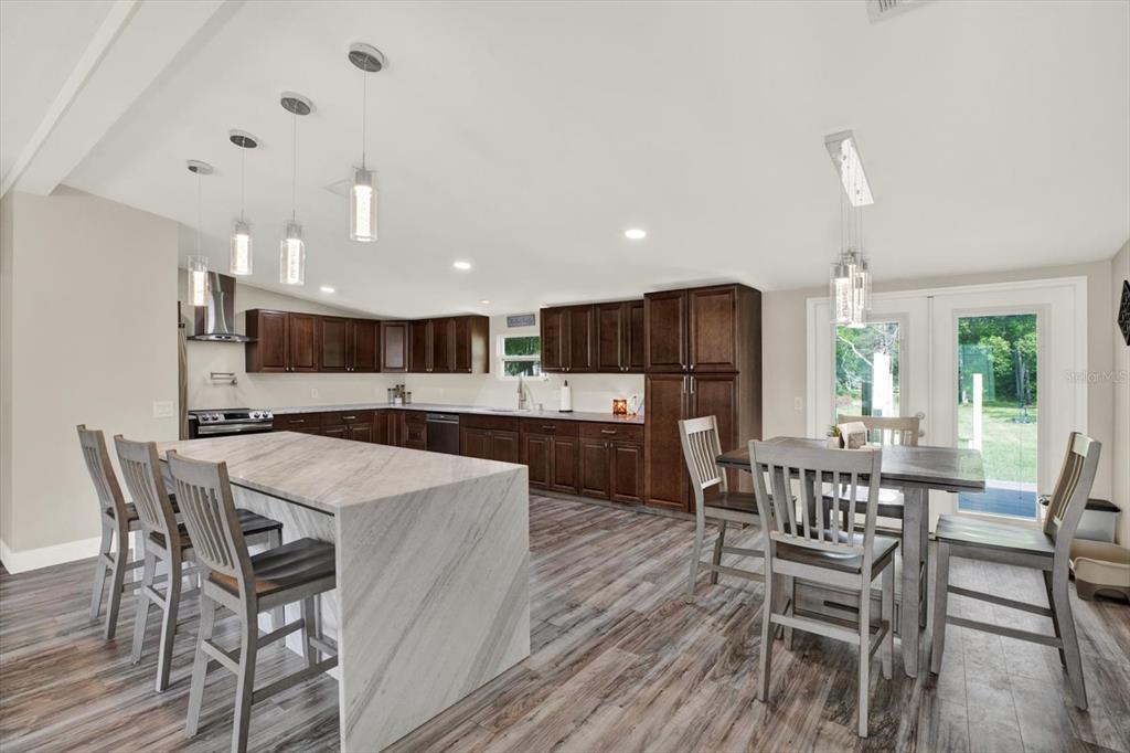 A kitchen with dark wood cabinets, a marble-topped island, and a dining area — 13611 MCINTOSH DRIVE, DADE CITY, FL