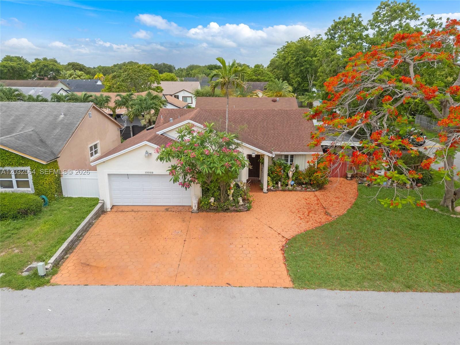 An aerial view shows a single-story house with a patterned orange driveway and flowering trees — 13332 SW 113th Ct, Miami FL 33176, MIAMI, FL