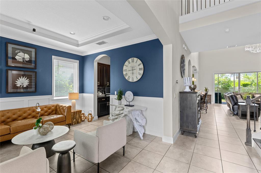 A living room features a blue accent wall, white wainscoting, a leather sofa, and tile flooring — 8802 FINSEN STREET, ORLANDO, FL