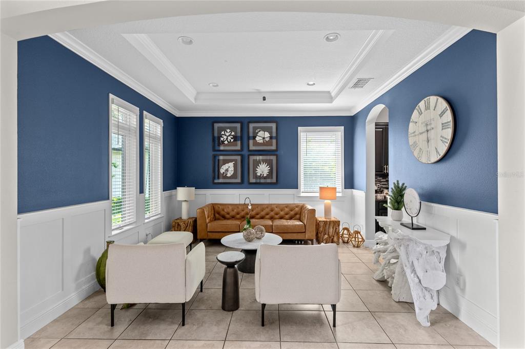 A living room features blue walls, white wainscoting, a leather sofa, and two cream armchairs — 8802 FINSEN STREET, ORLANDO, FL