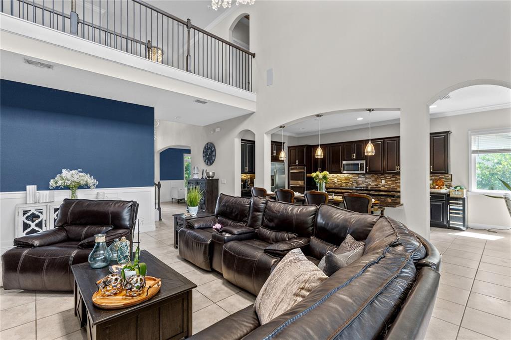 A living room with a sectional sofa, dark wood furniture, and an open kitchen area — 8802 FINSEN STREET, ORLANDO, FL