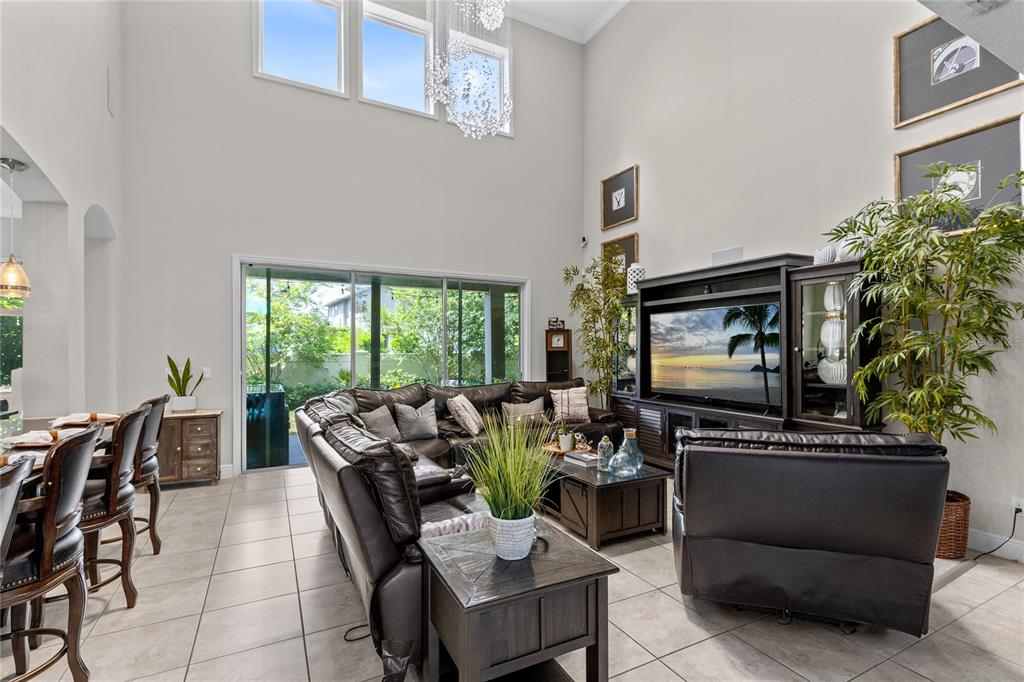 A living room with high ceilings, tile floors, a large sectional, and a television console — 8802 FINSEN STREET, ORLANDO, FL