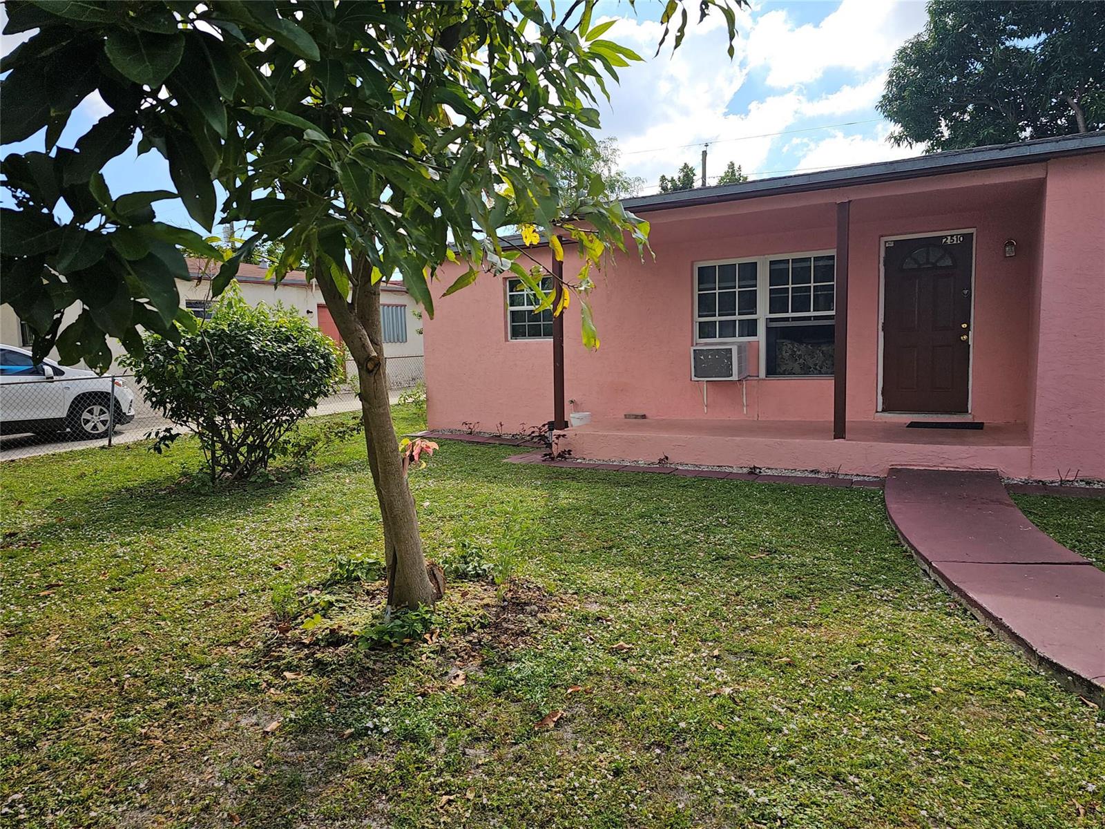 A pink single-story house features a front porch, a brown door, and a grassy yard — 2510 NW 6 Street, Pompano Beach FL 33069, POMPANO BEACH, FL