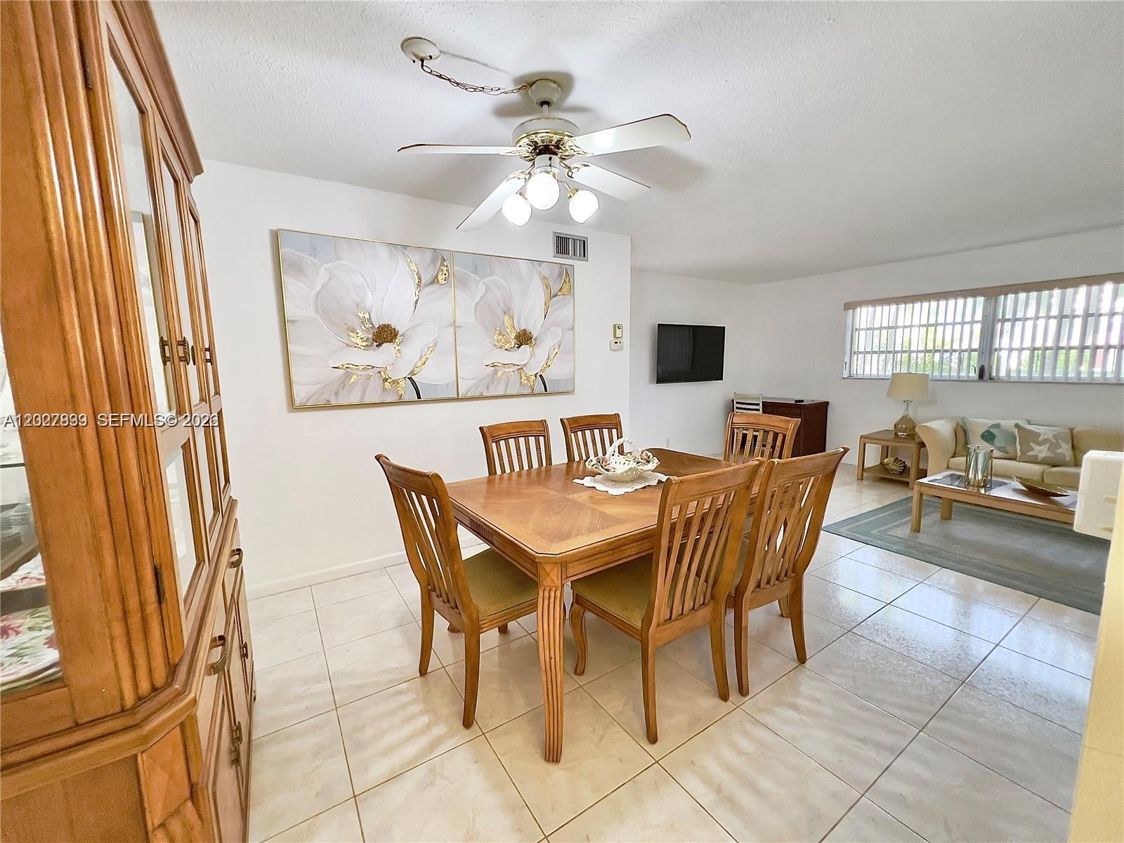 A dining area with a wooden table and chairs sits adjacent to a living room — HALLANDALE BEACH, FL