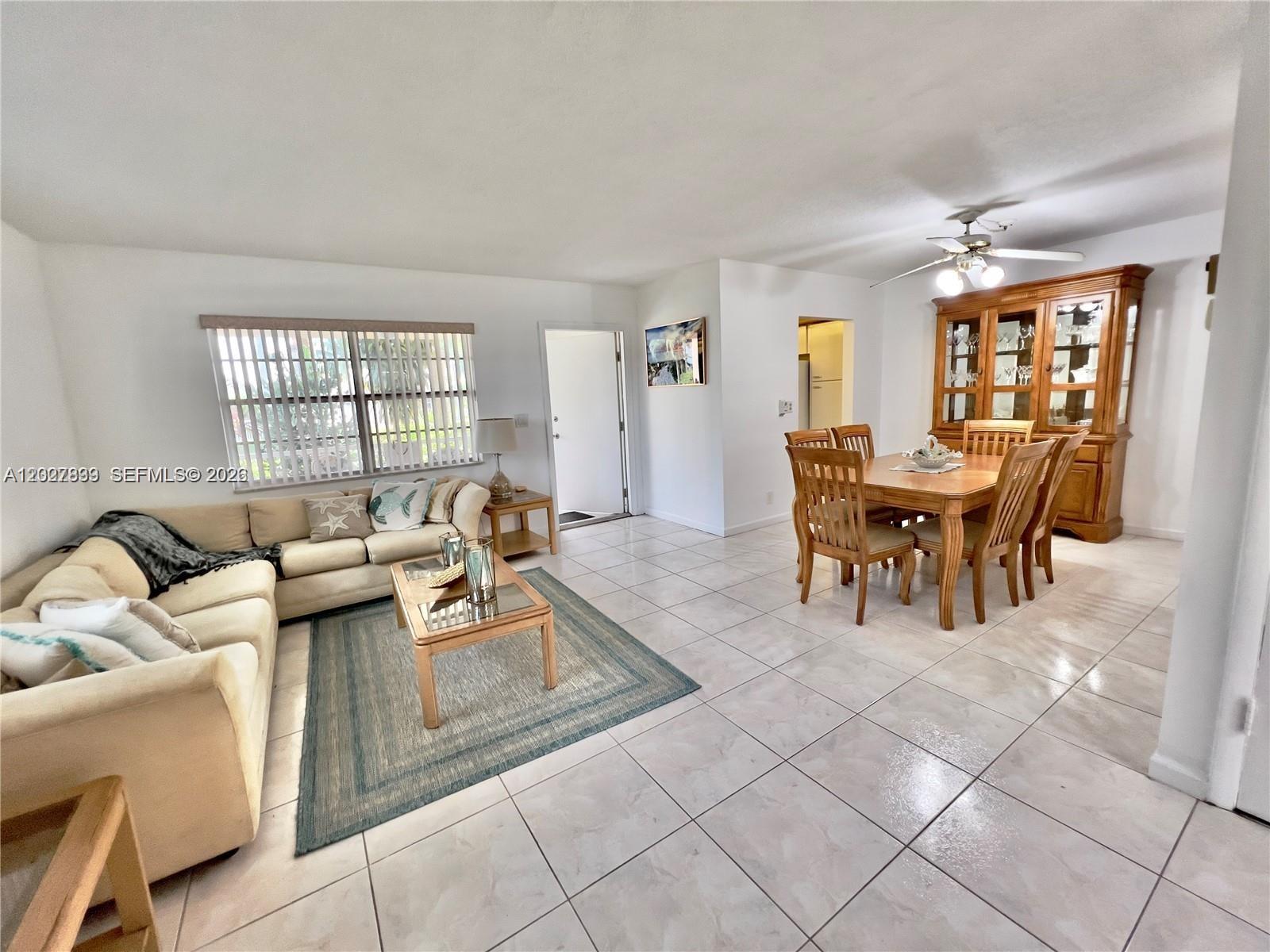 A living and dining area features tile flooring, a beige sectional sofa, and wooden furniture — HALLANDALE BEACH, FL