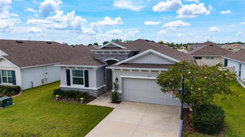 A single-story suburban house with a gray exterior, stone accents, and a two-car garage — 8611 SW 49TH CIRCLE, OCALA, FL