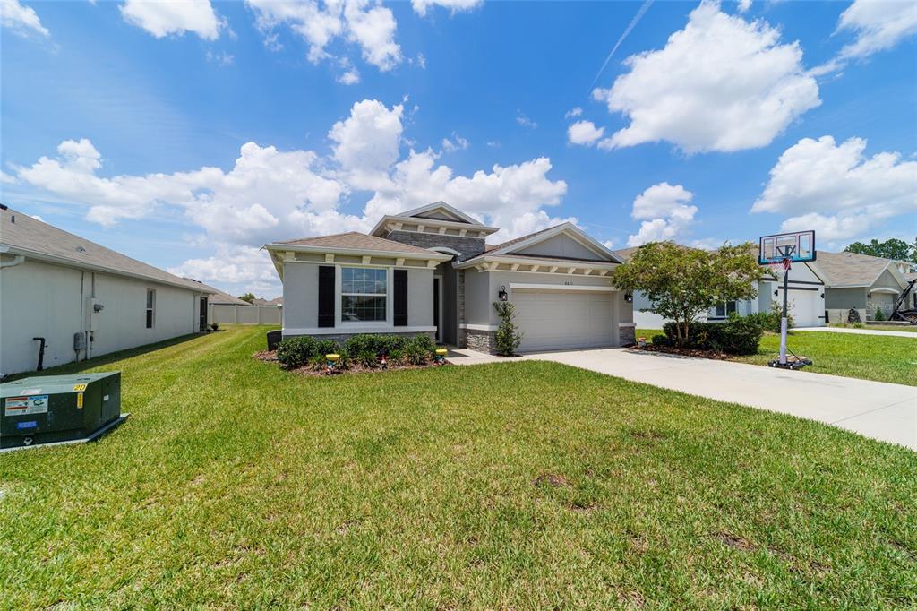 A single-story suburban house features a two-car garage, stone accents, and a grassy front yard — 8611 SW 49TH CIRCLE, OCALA, FL