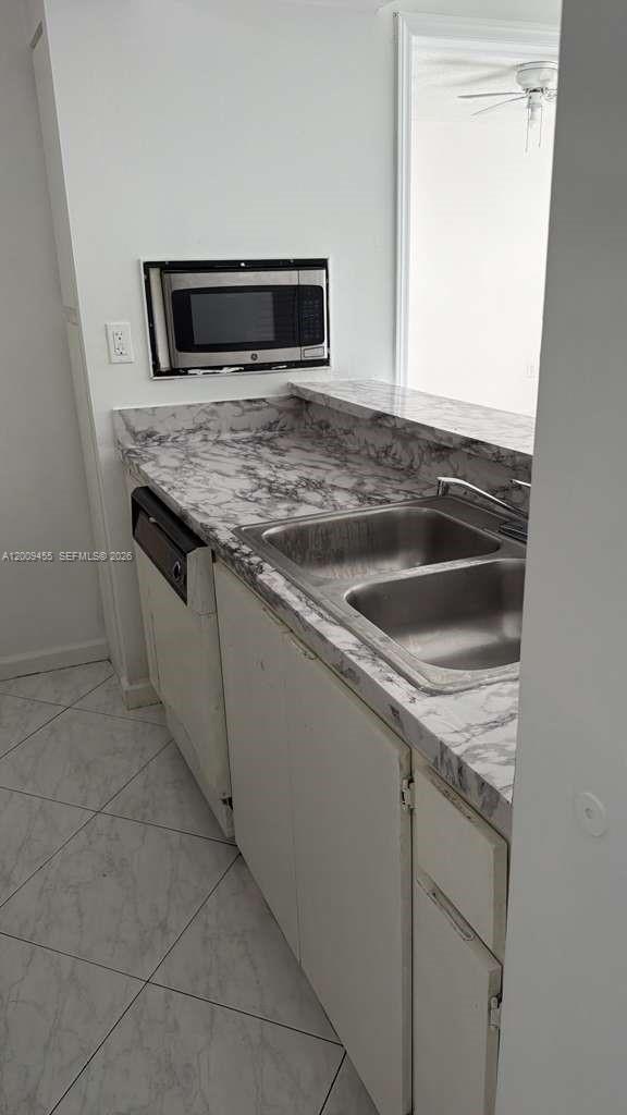 A kitchen features a double-basin sink, marble-patterned countertops, and a built-in microwave — 6995 NW 186th St # E507, Hialeah FL 33015, HIALEAH, FL