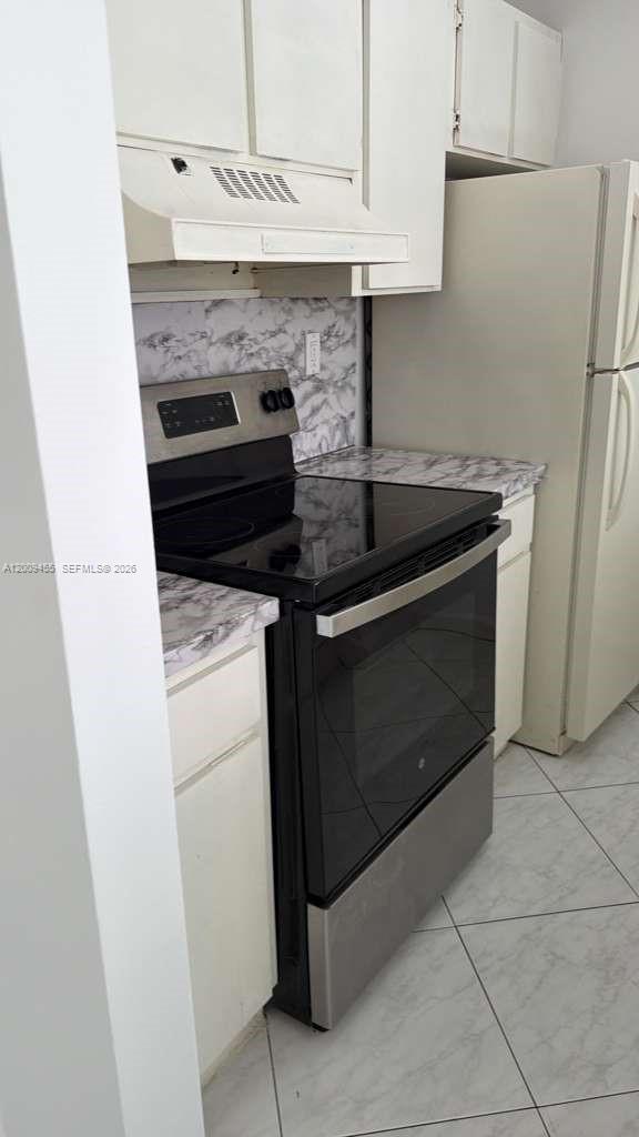 A kitchen features white cabinets, a black electric stove, and marble-patterned countertops — 6995 NW 186th St # E507, Hialeah FL 33015, HIALEAH, FL