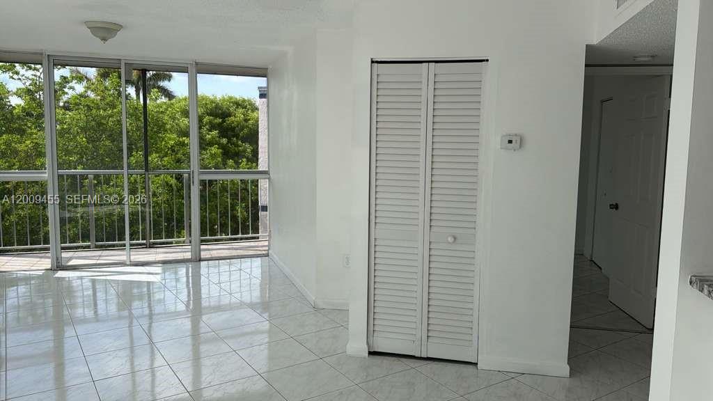A room with white tile flooring, a louvered closet door, and a sliding glass balcony door — 6995 NW 186th St # E507, Hialeah FL 33015, HIALEAH, FL