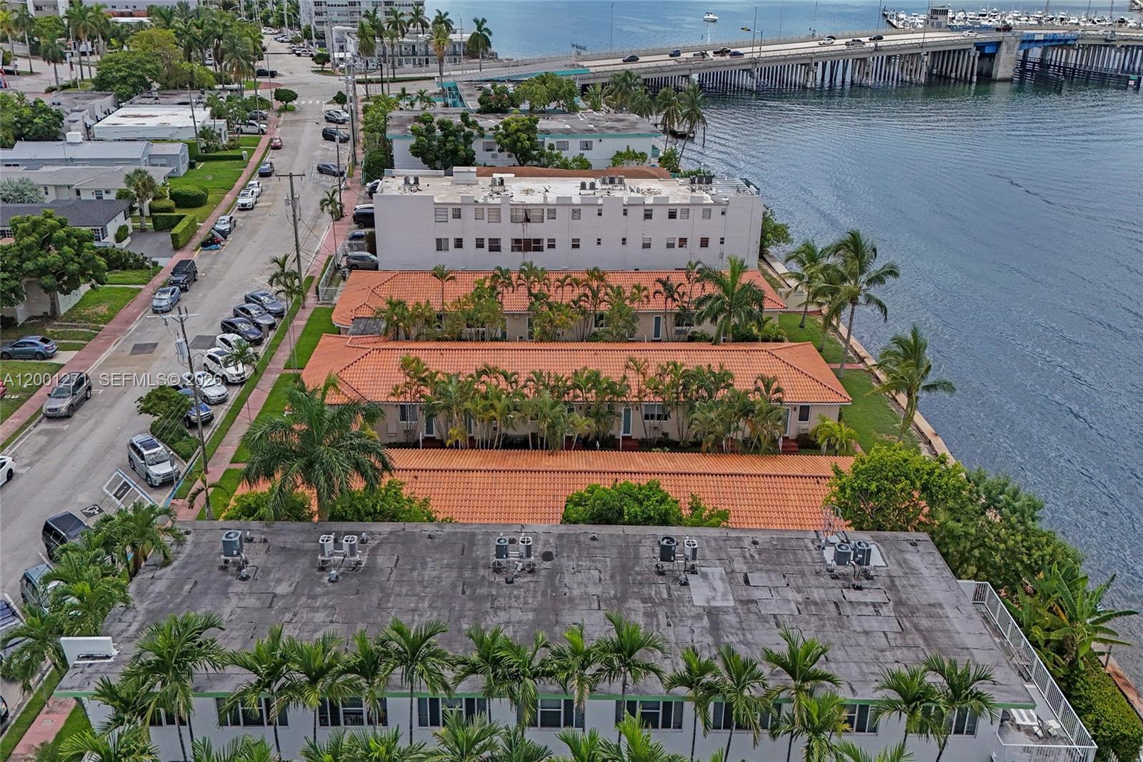 An aerial view shows residential buildings with orange tile roofs situated along a waterfront — 2170 Bay Dr # 20, Miami Beach FL 33141, MIAMI BEACH, FL