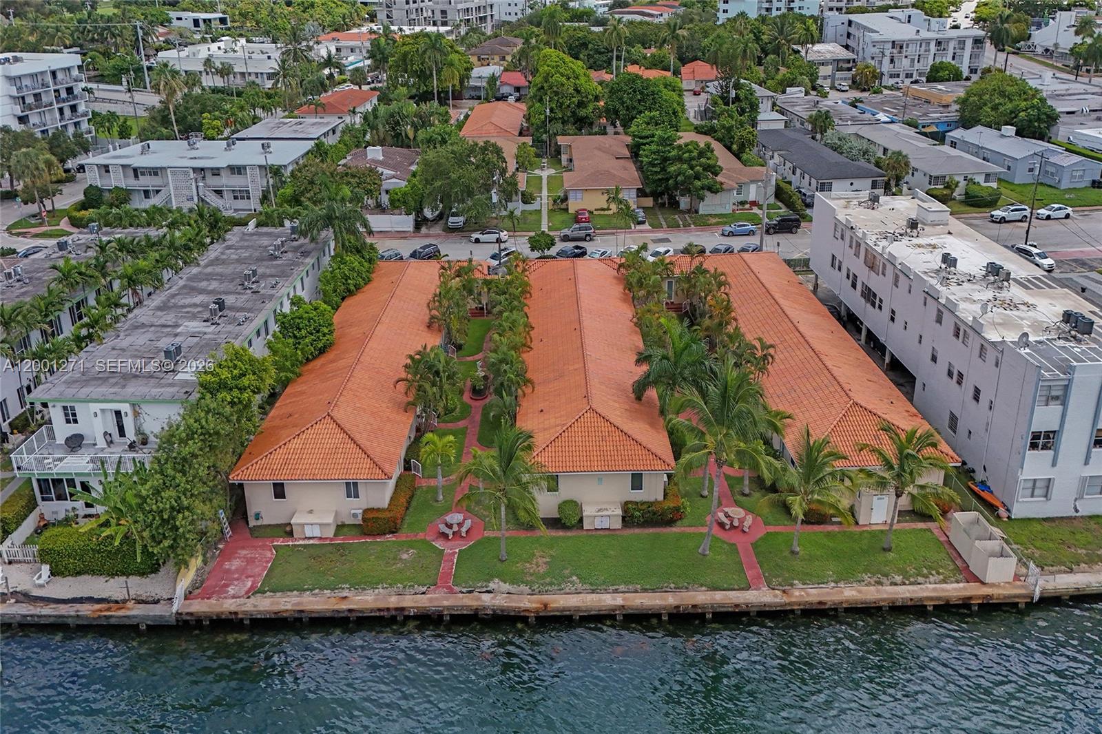 An aerial view shows three connected waterfront buildings with orange tile roofs and palm trees — 2170 Bay Dr # 20, Miami Beach FL 33141, MIAMI BEACH, FL