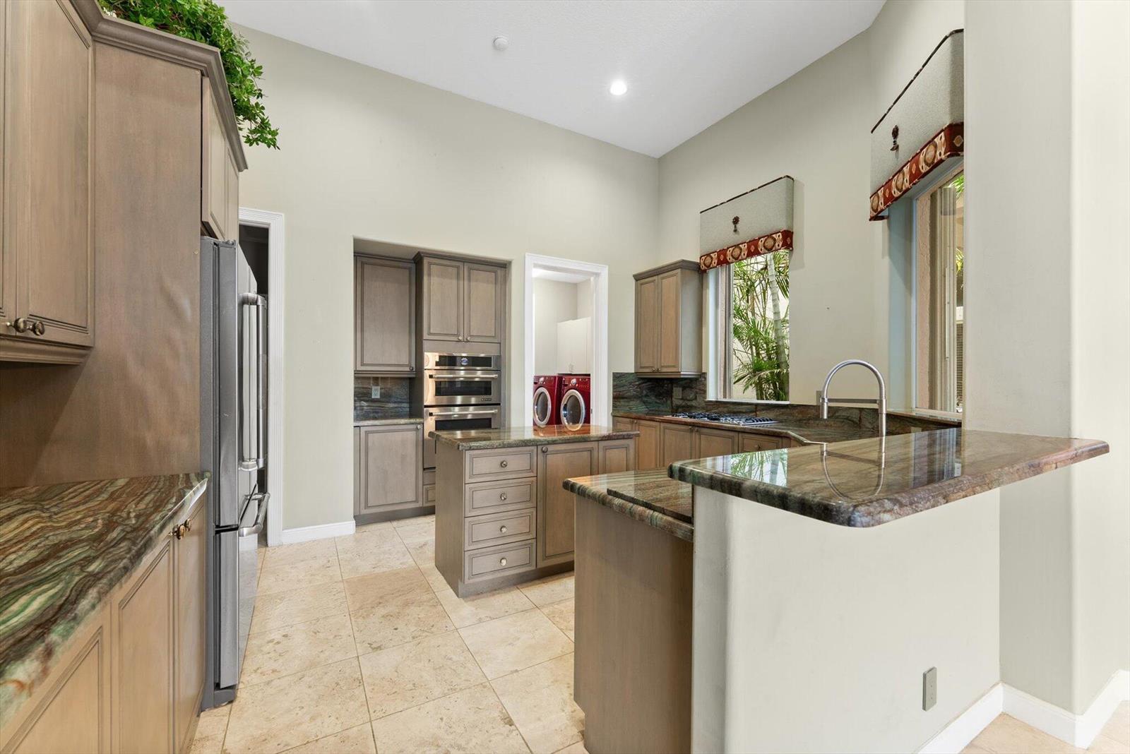 A kitchen features wood cabinets, granite countertops, stainless steel appliances, and a central island — 7081 Mallorca Crescent, Boca Raton FL 33433, BOCA RATON, FL