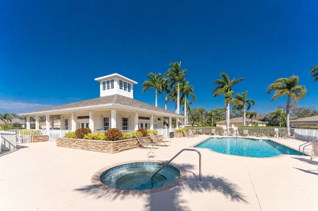 An outdoor swimming pool and hot tub sit in front of a community clubhouse building — 29633 NIAGARA COURT, ENGLEWOOD, FL
