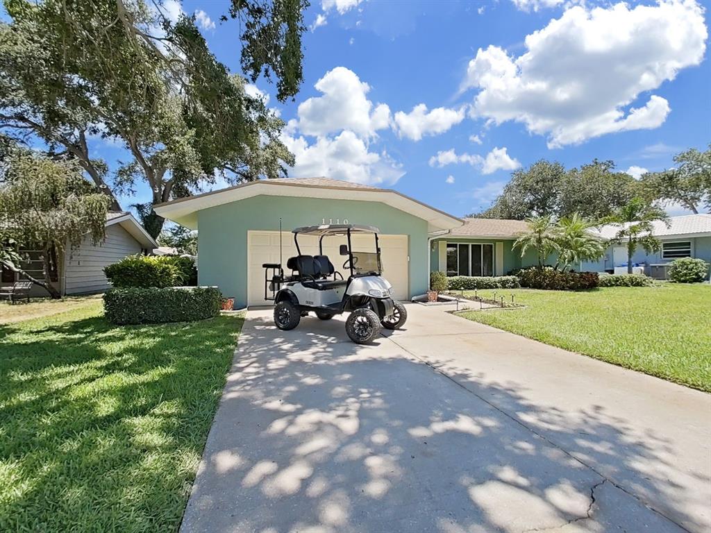A light green single-story house with a golf cart parked in the driveway — 1110 MCLEAN STREET, DUNEDIN, FL