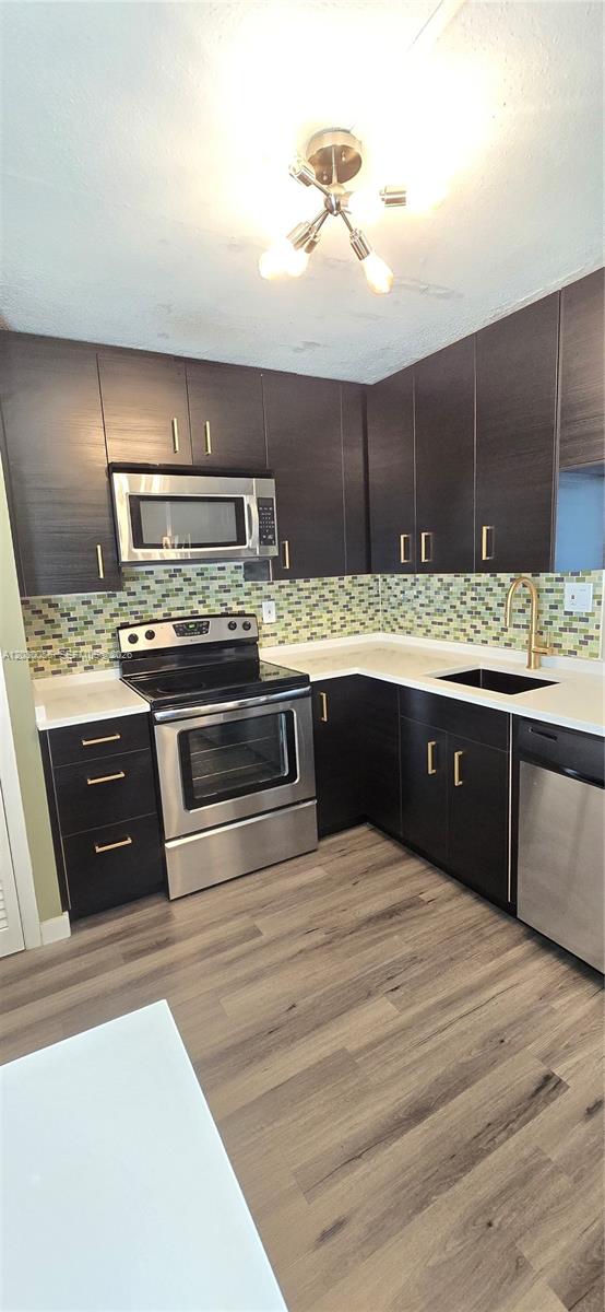 A kitchen features dark wood cabinets, stainless steel appliances, white countertops, and a mosaic backsplash — 1201 NE 191st St # G306, Miami FL 33179, MIAMI, FL