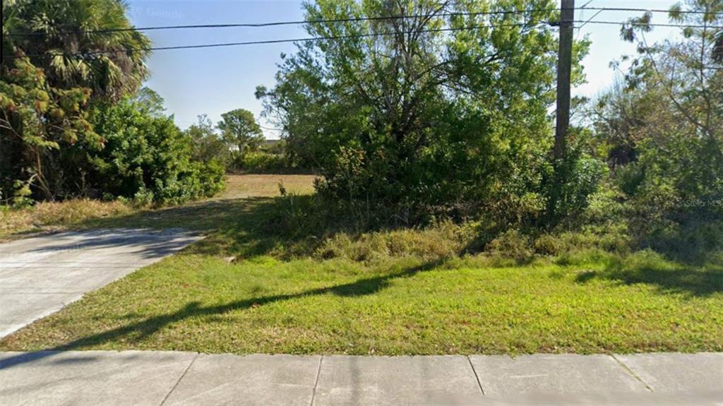 A vacant, overgrown residential lot features a concrete driveway apron and mature trees — 1828 COOPER STREET, PUNTA GORDA, FL