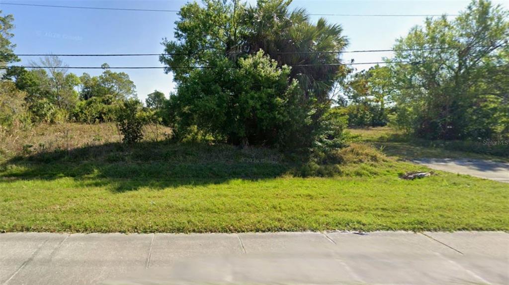 A vacant, grassy lot with trees and shrubs sits behind a concrete sidewalk — 1828 COOPER STREET, PUNTA GORDA, FL